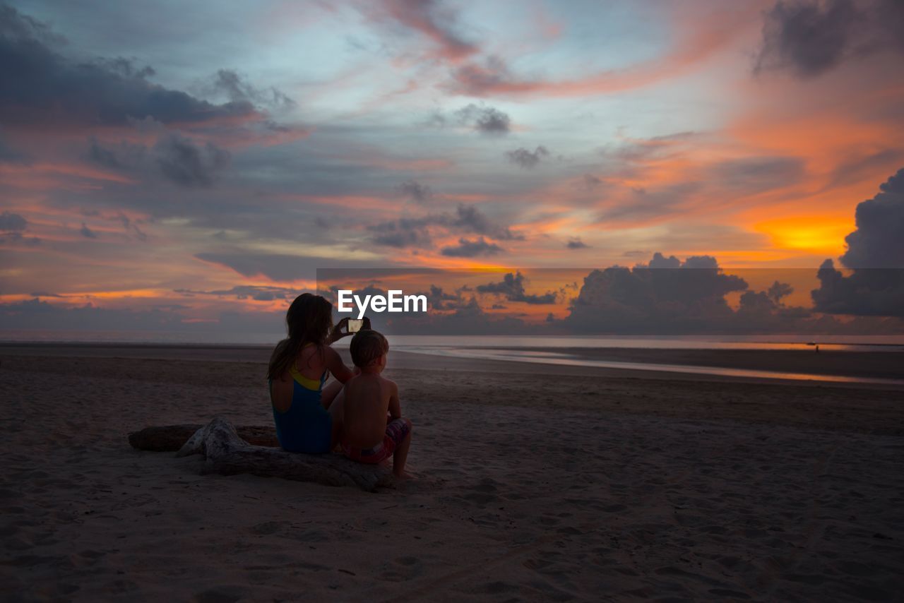 COUPLE SITTING ON BEACH DURING SUNSET