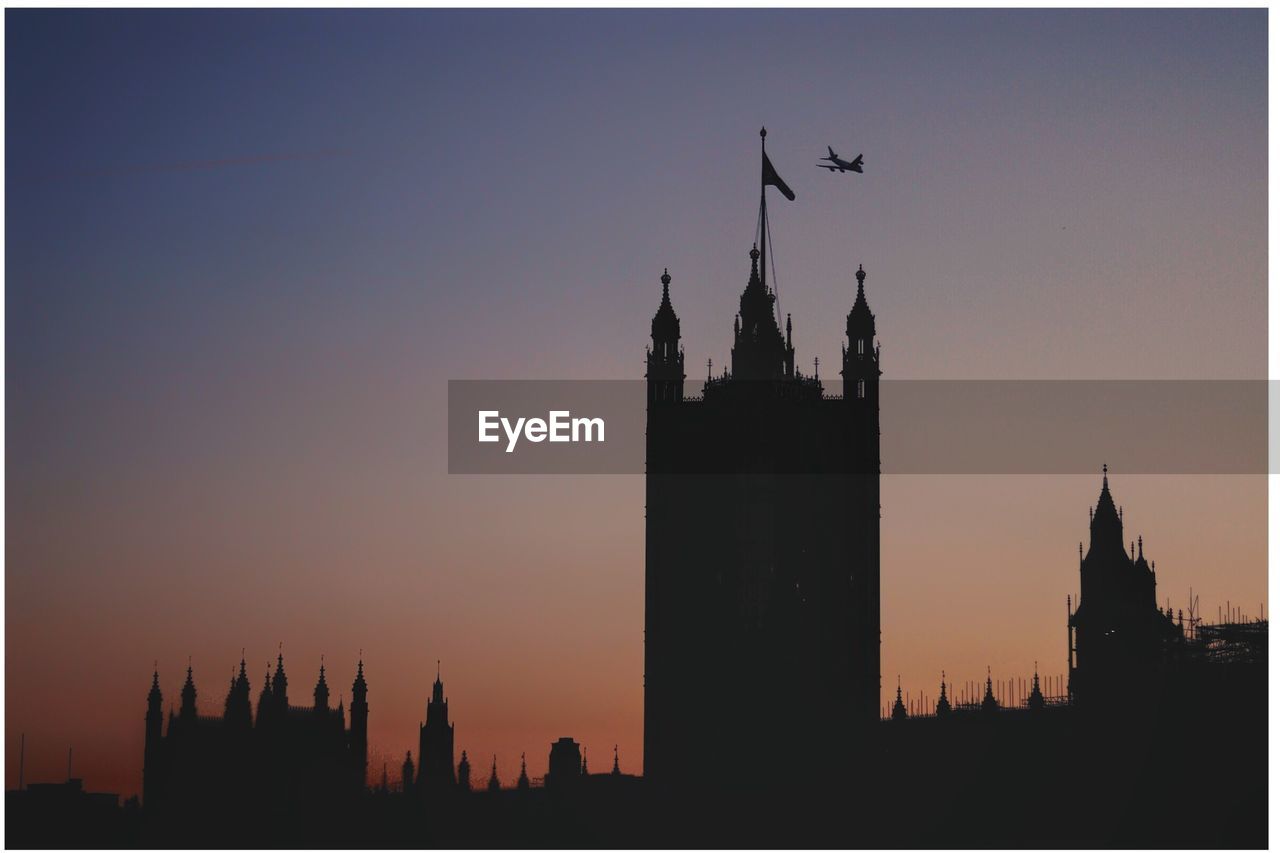 Silhouette of buildings in city at sunset