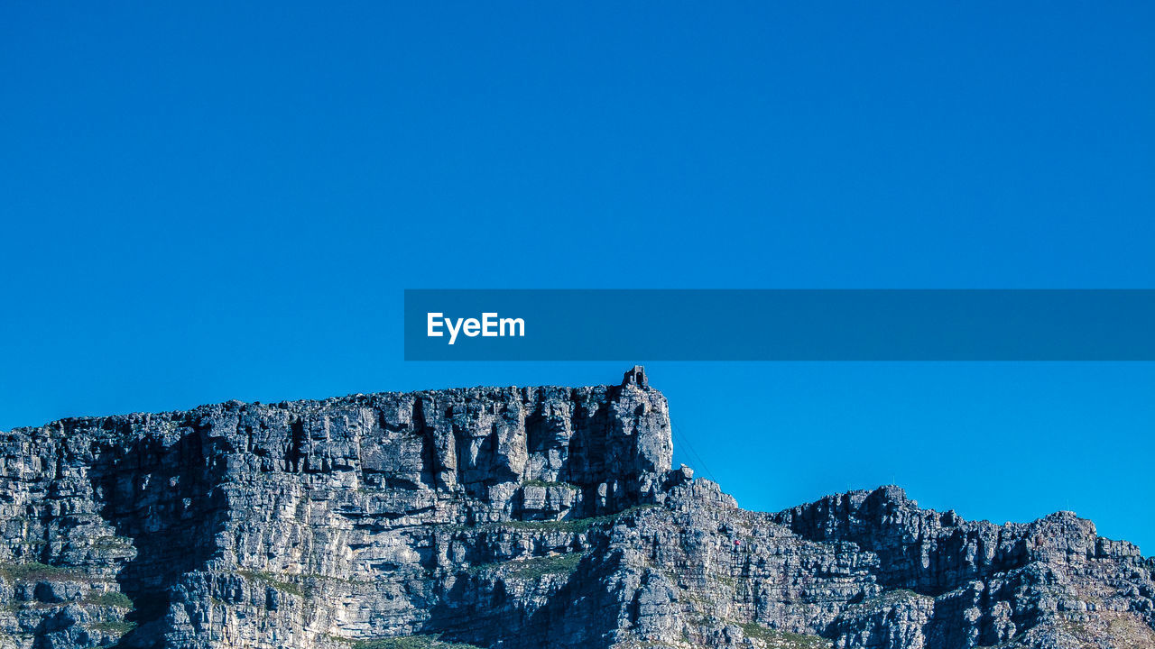 Low angle view of rock formation against clear blue sky