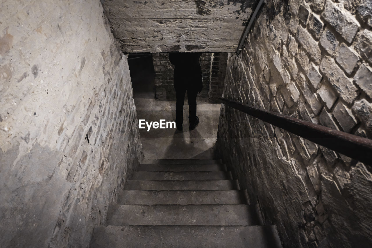 REAR VIEW OF MAN ON STAIRCASE IN TUNNEL