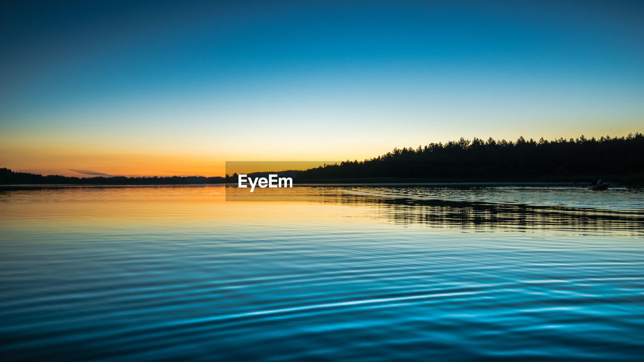 Scenic view of lake against clear sky at sunset