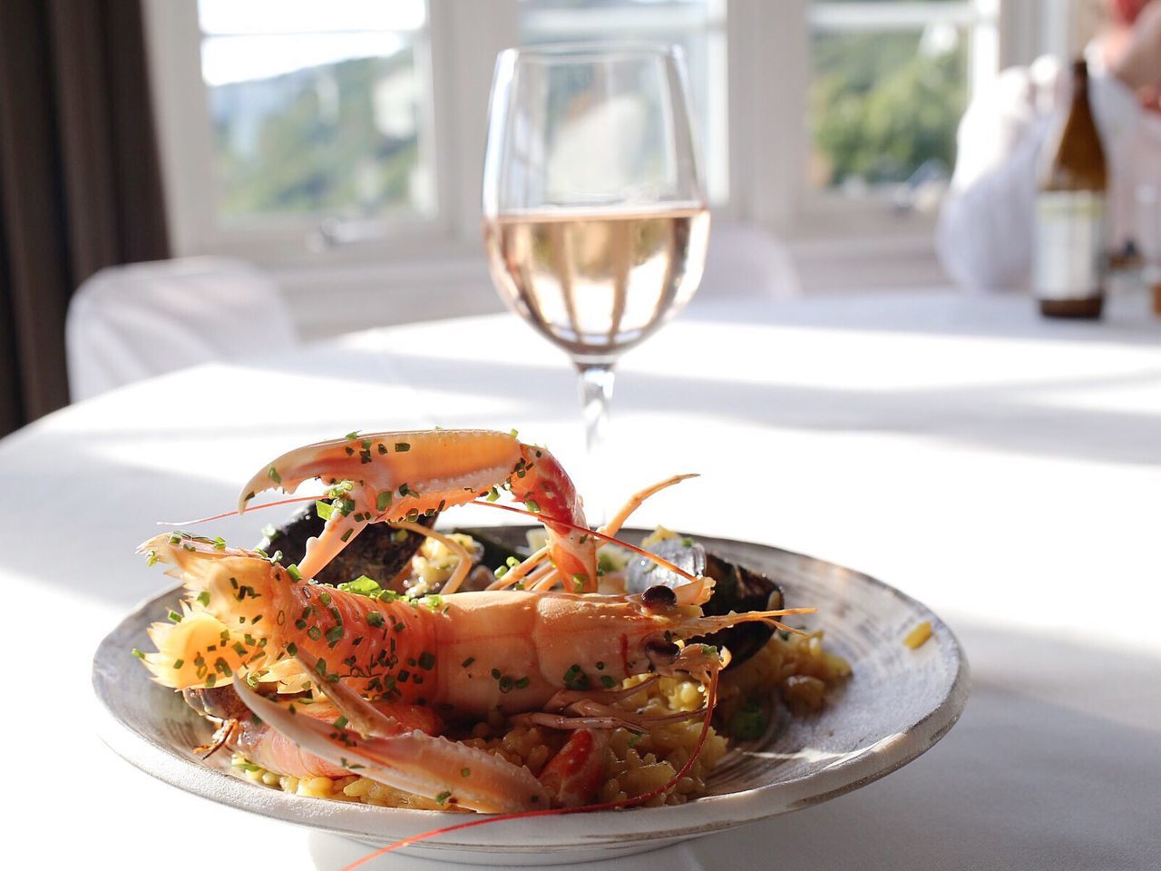 Close-up of paella served with white wine on table in restaurant