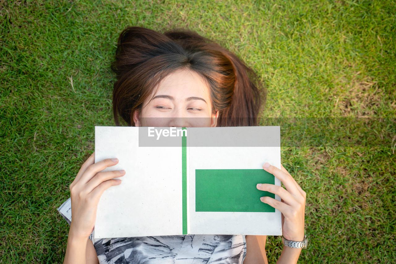 High angle view of woman with book lying on land