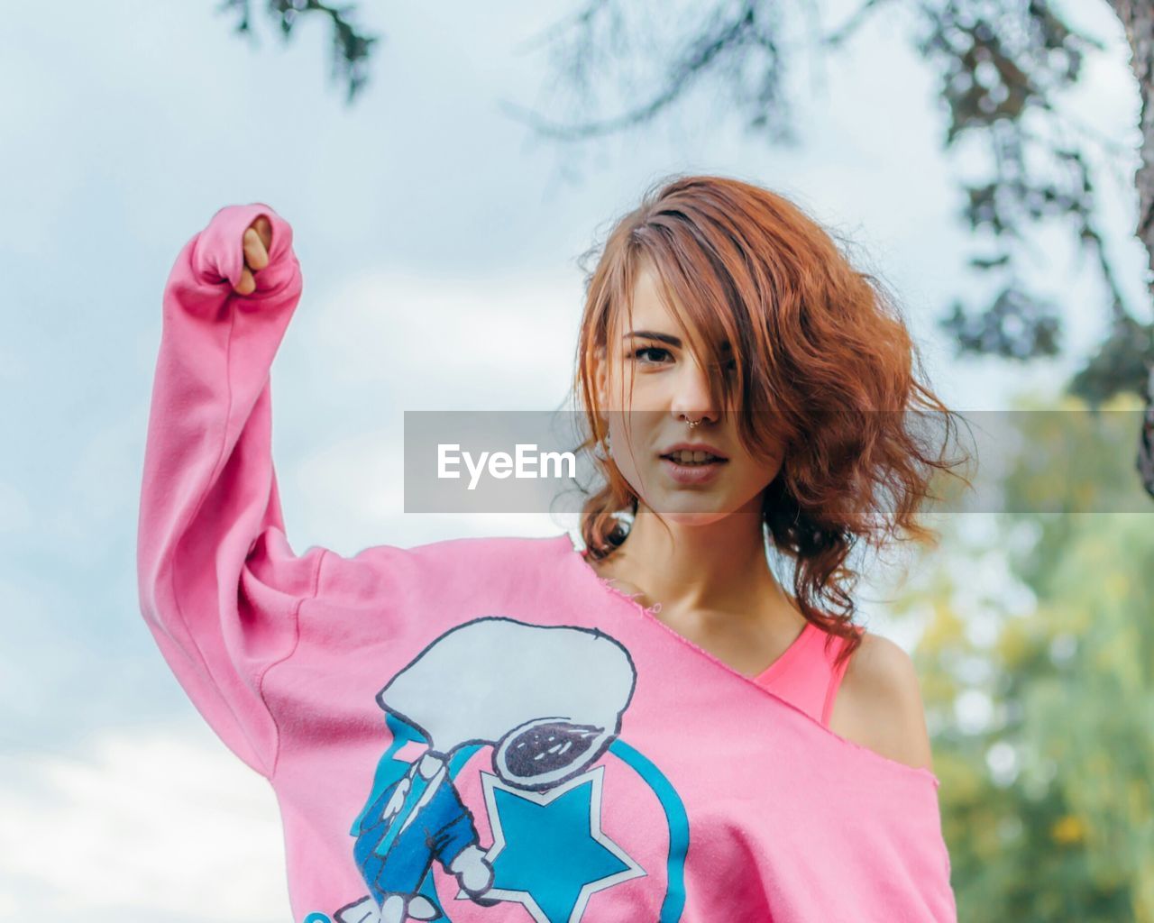 Portrait of happy young woman standing against sky