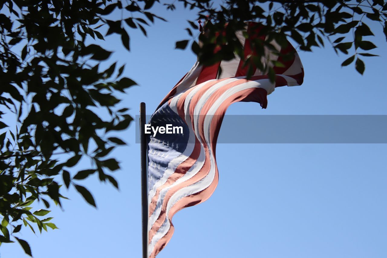 Low angle view of flag waving against clear blue sky