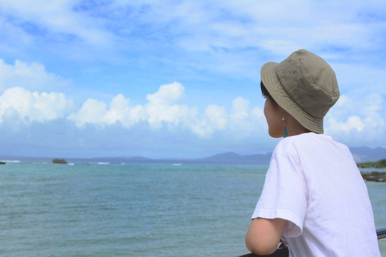 Side view of thoughtful woman looking at sea against cloudy sky