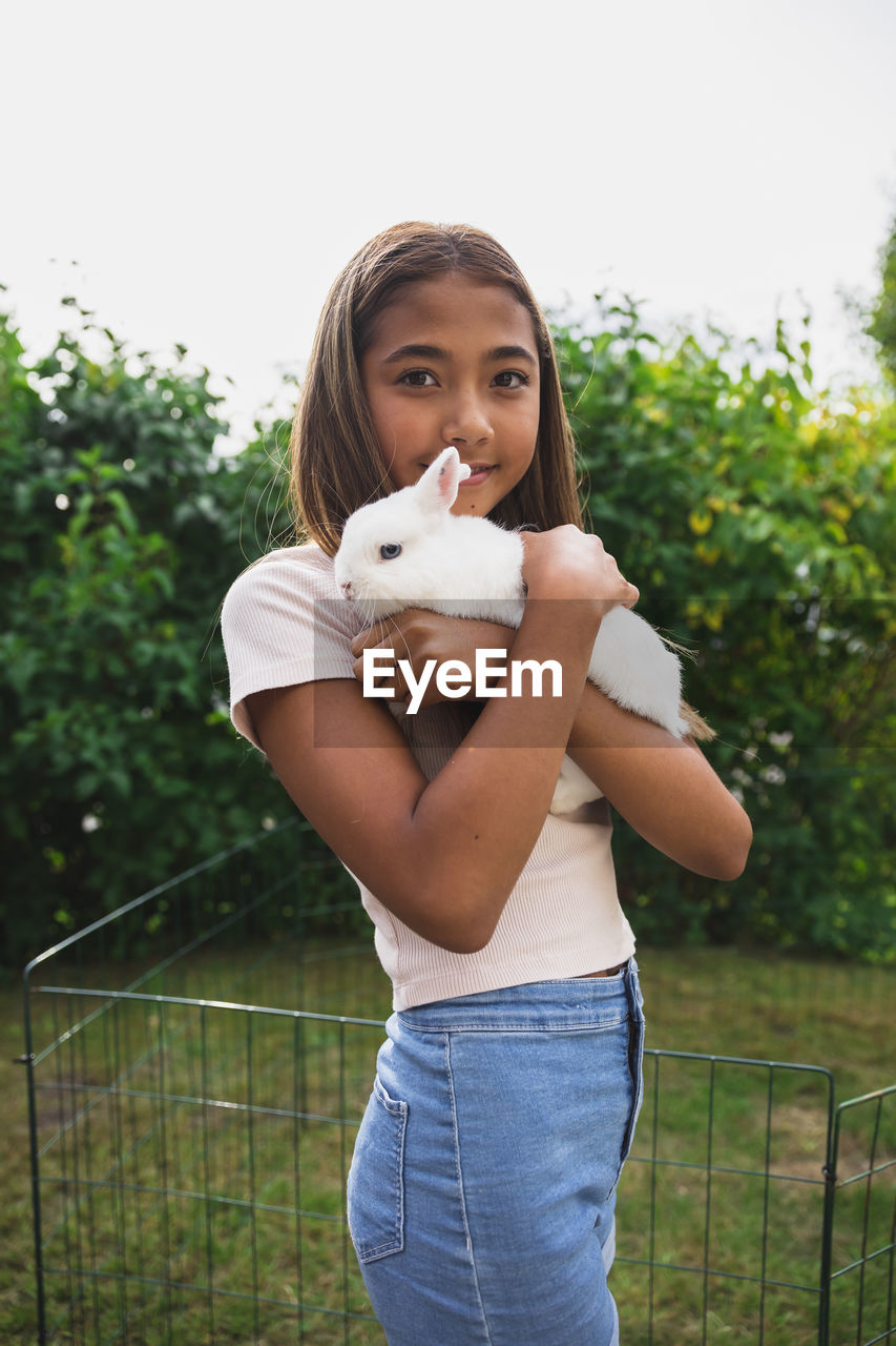 Girl holding rabbit in back yard