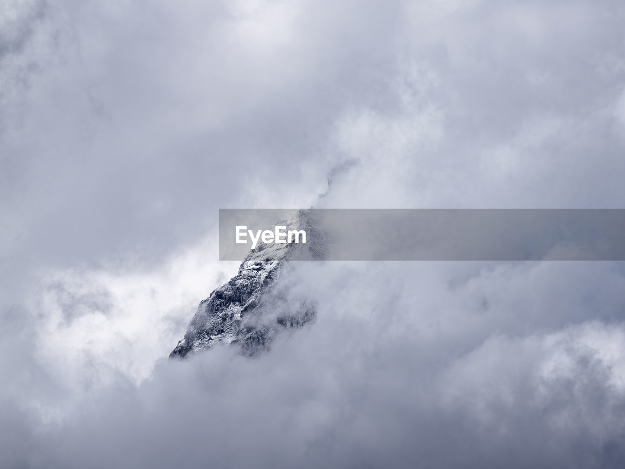 low angle view of snow covered mountain against cloudy sky