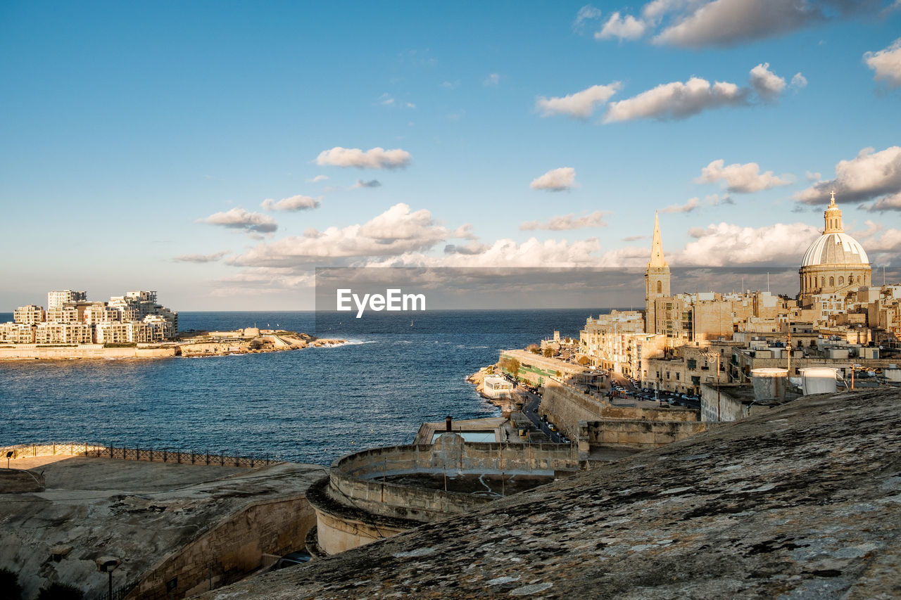 PANORAMIC VIEW OF SEA BY BUILDINGS AGAINST SKY
