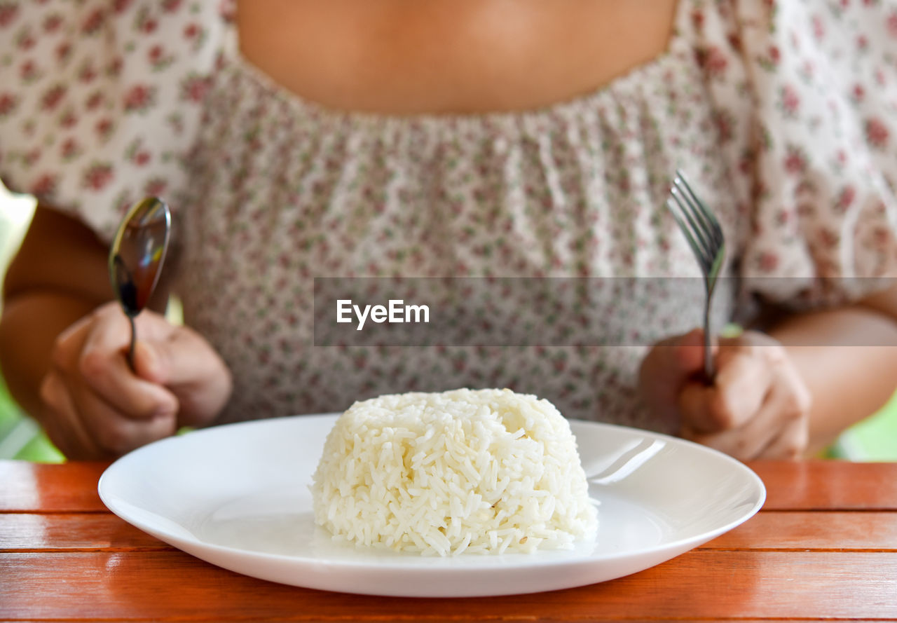 food and drink, food, one person, eating utensil, plate, women, adult, kitchen utensil, dish, midsection, fork, table, meal, indoors, baked, wellbeing, sitting, front view, holding, healthy eating, spoon, hand, eating, lifestyles, freshness, jasmine rice, sweet food, breakfast, child, crockery, casual clothing, sweet, female, dinner, cuisine, young adult, dessert, produce, focus on foreground