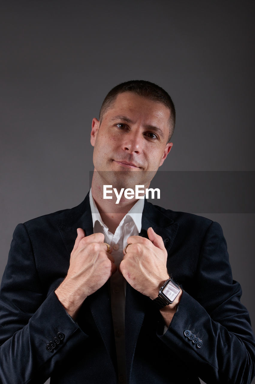 Portrait of man standing against black background