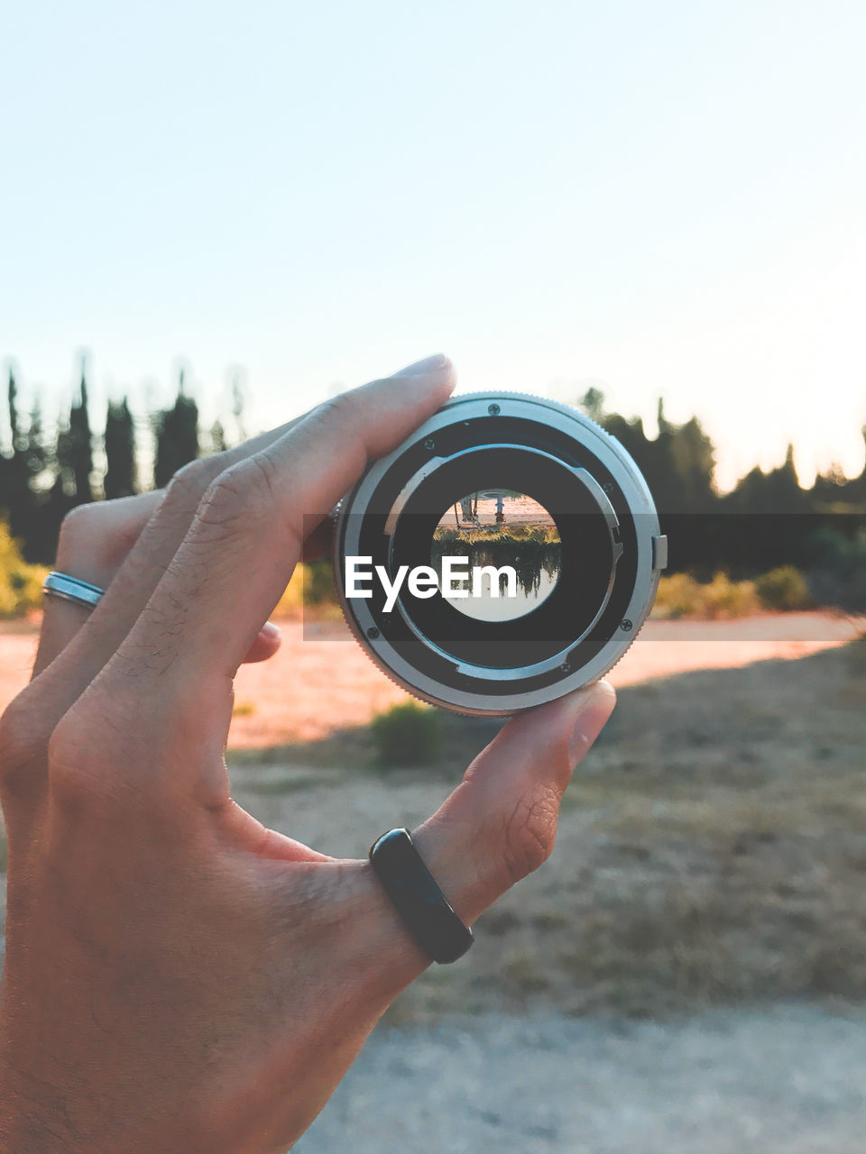 Close-up of hand holding lens against sky