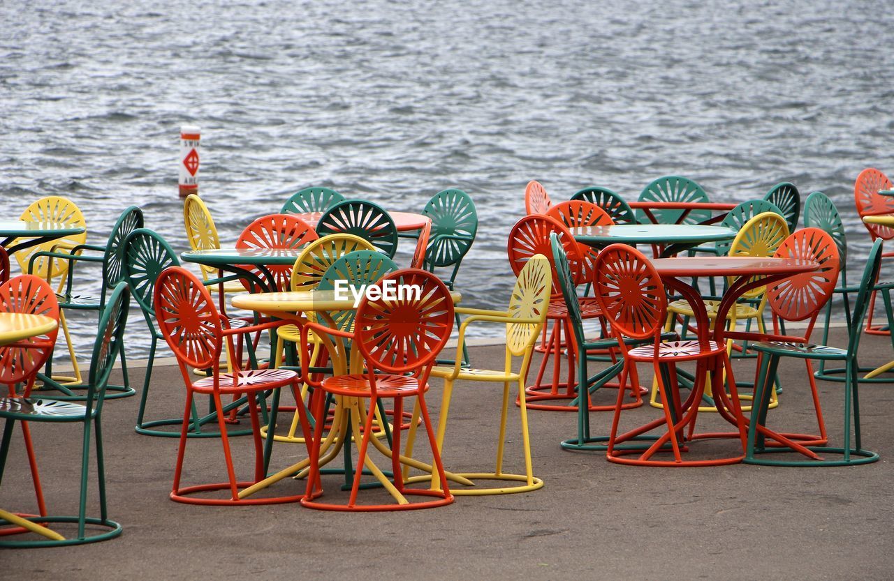 Colorful chairs on walkway against sea