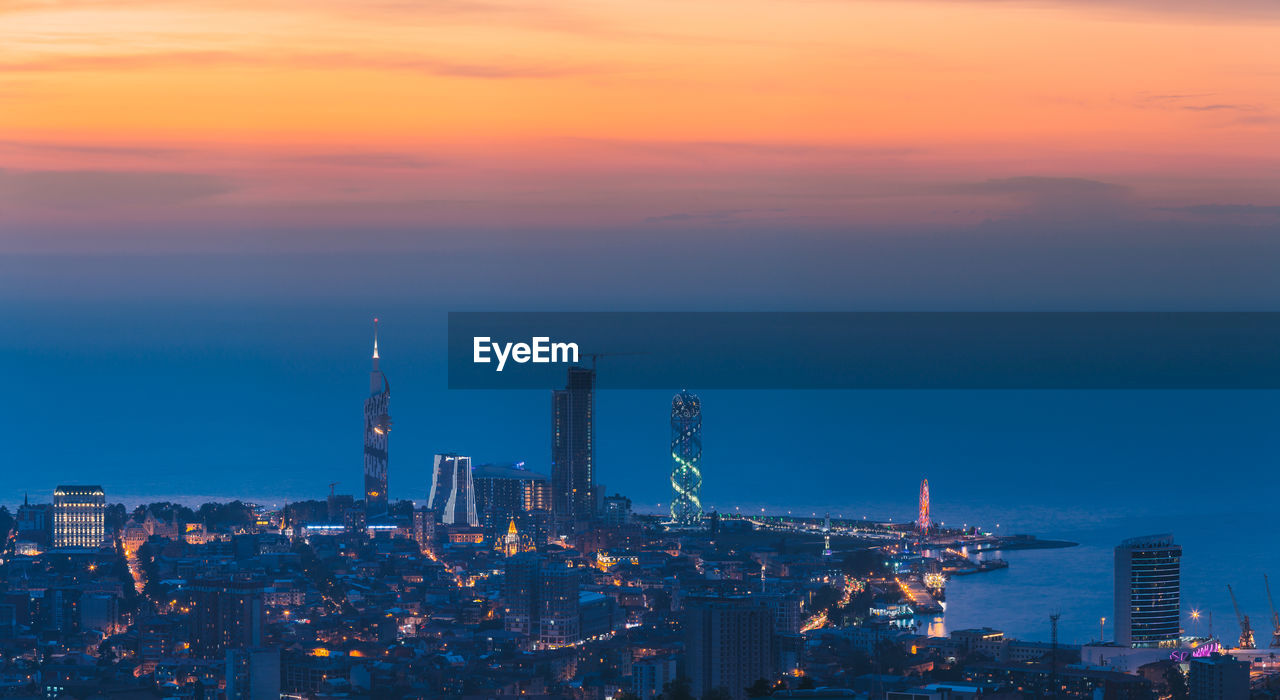 high angle view of illuminated cityscape against sky during sunset