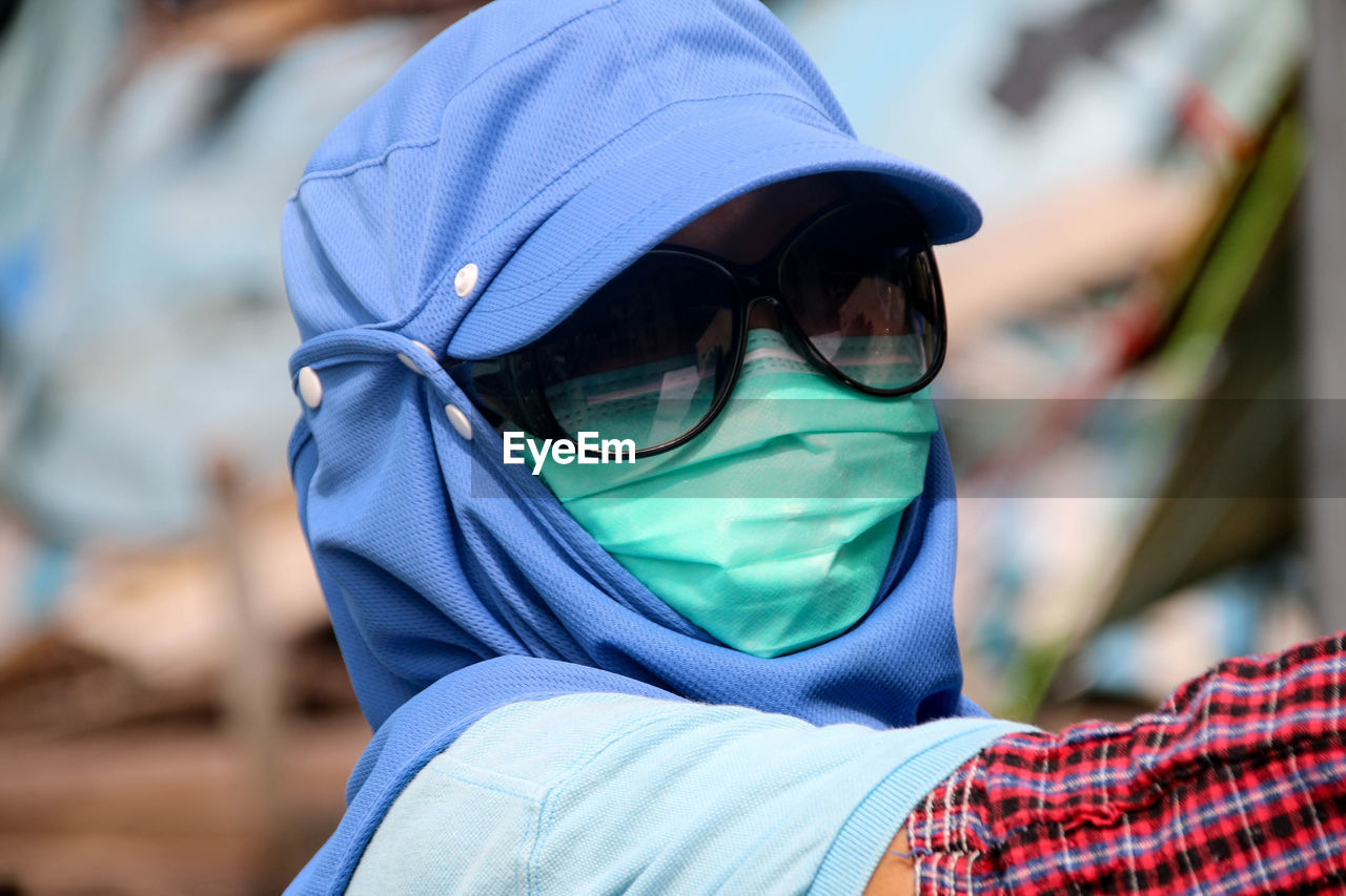 CLOSE-UP OF WOMAN WEARING SUNGLASSES AGAINST BLURRED BACKGROUND