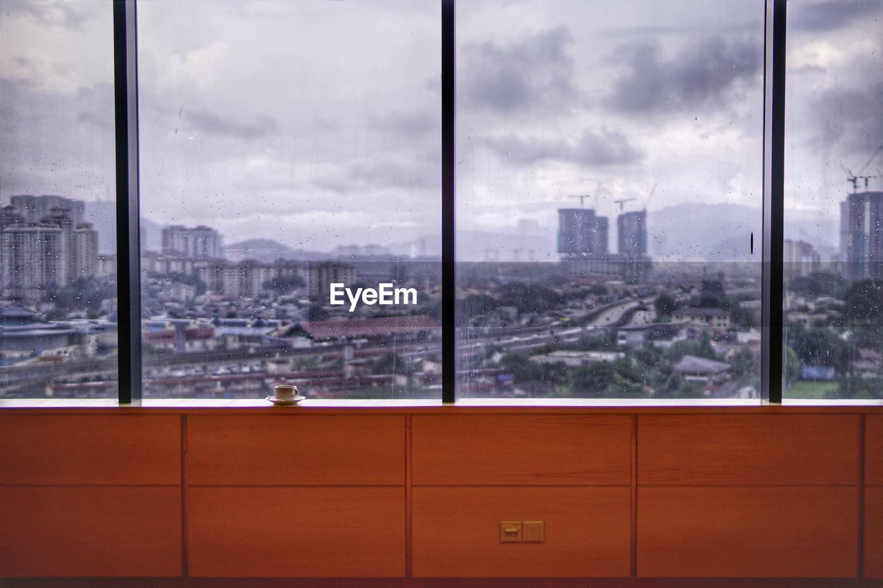 Buildings against sky seen through glass window