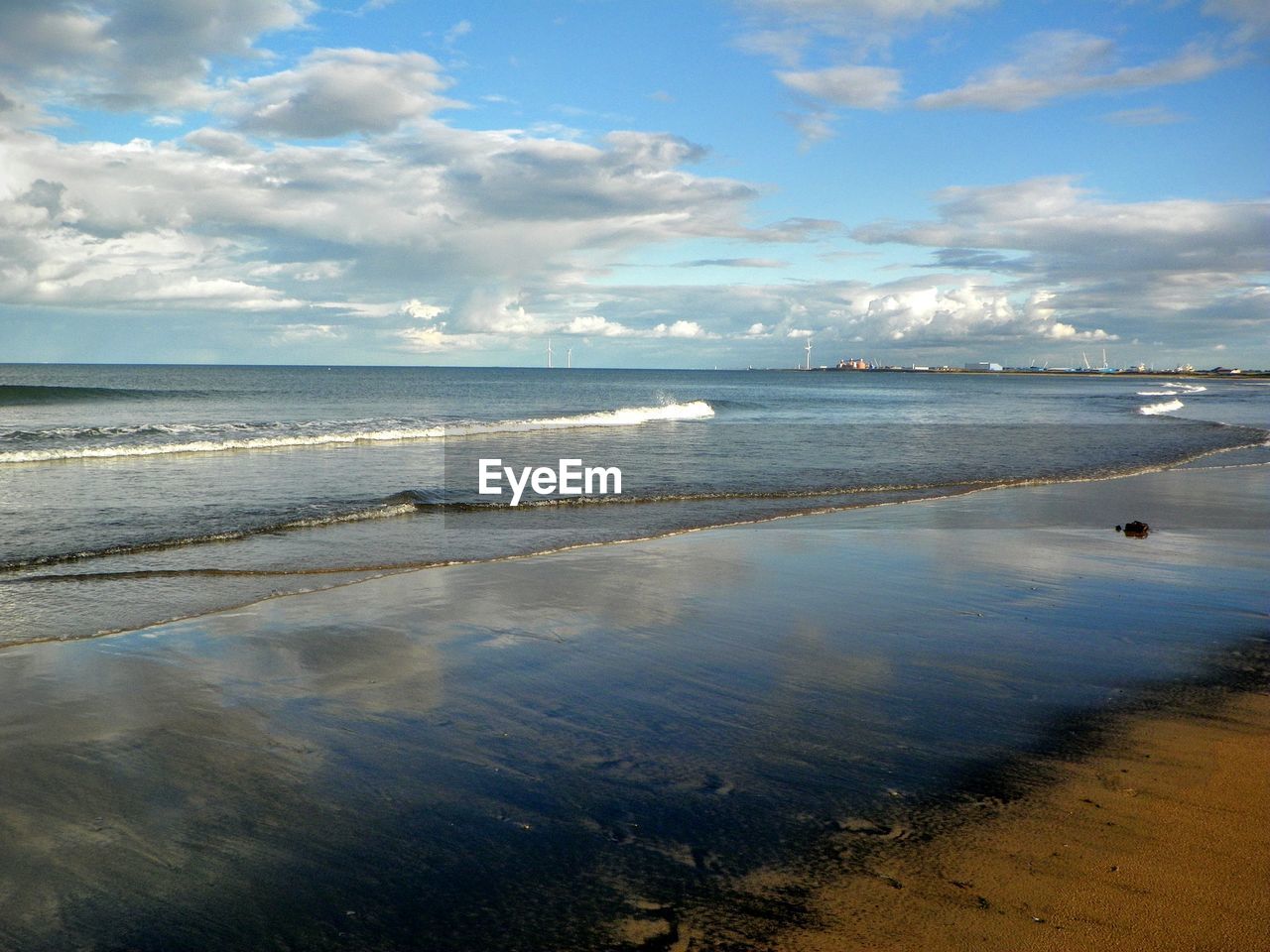 Scenic view of sea against sky with reflections of the sky on the wet sand