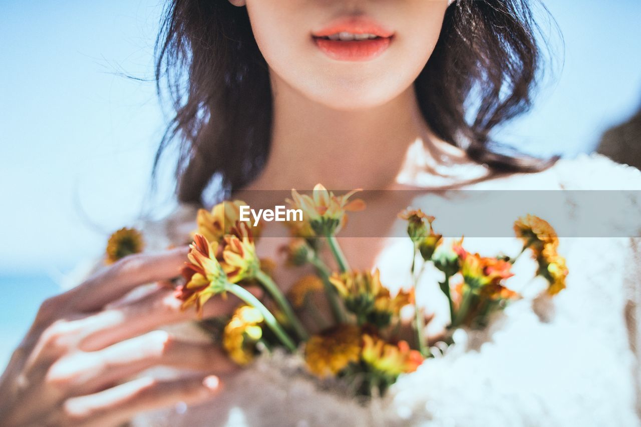 CLOSE-UP OF YOUNG WOMAN WITH FLOWERS