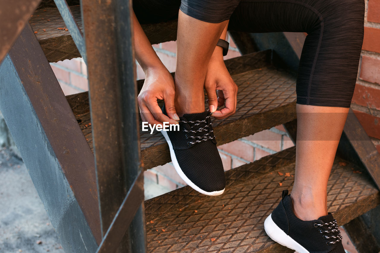 Low section of woman tying shoelace on metallic steps