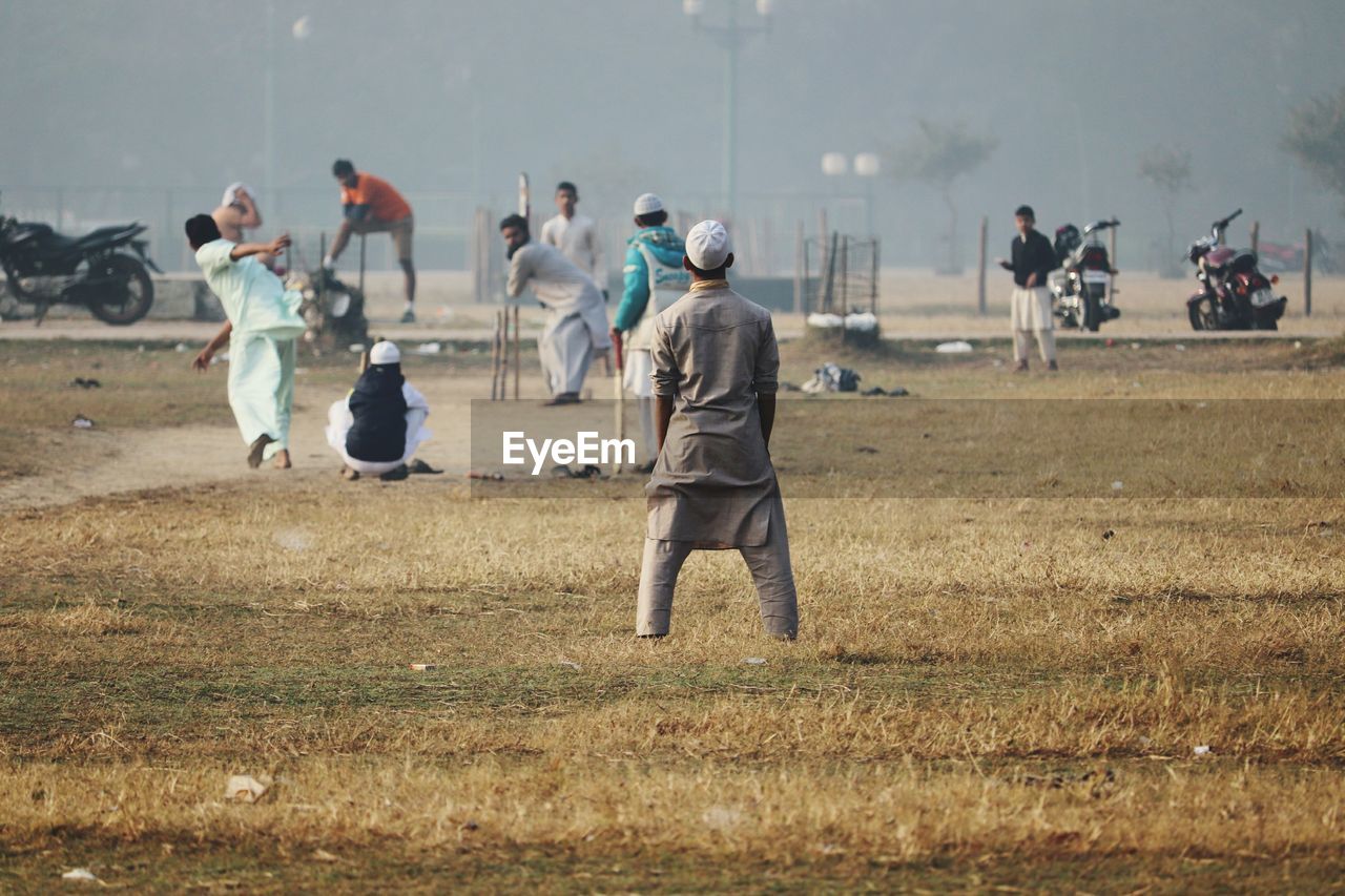 People playing cricket on field