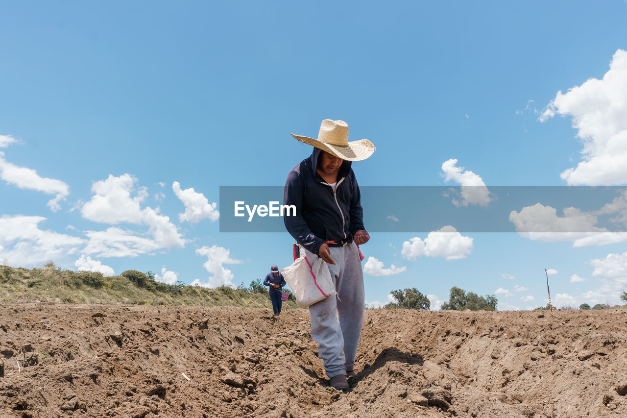 Rear view of woman standing on field against sky