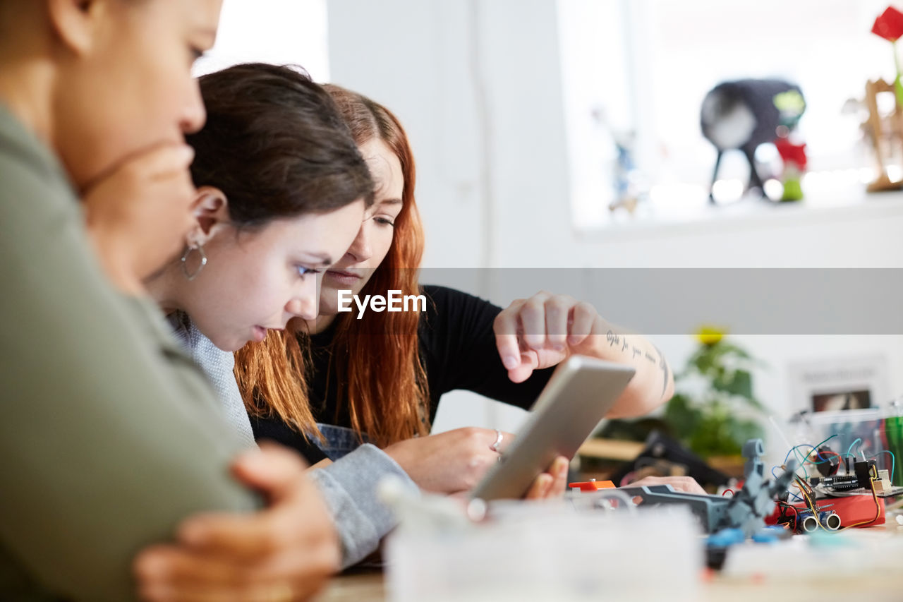 Multi-ethnic female engineers using digital tablet at table in workshop