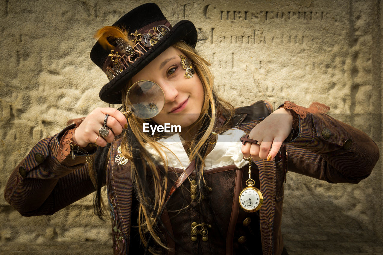 Portrait of young woman looking through magnifying glass