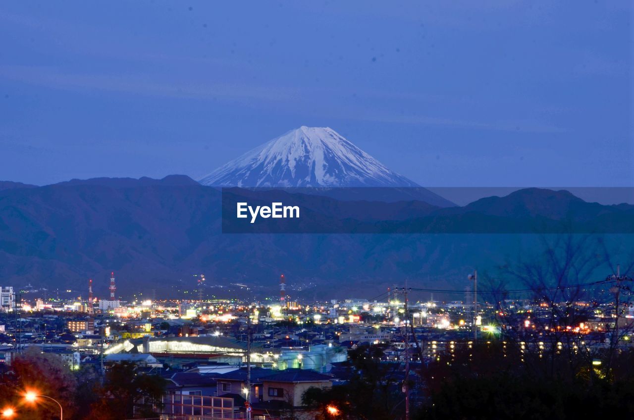 ILLUMINATED CITYSCAPE AGAINST CLEAR BLUE SKY