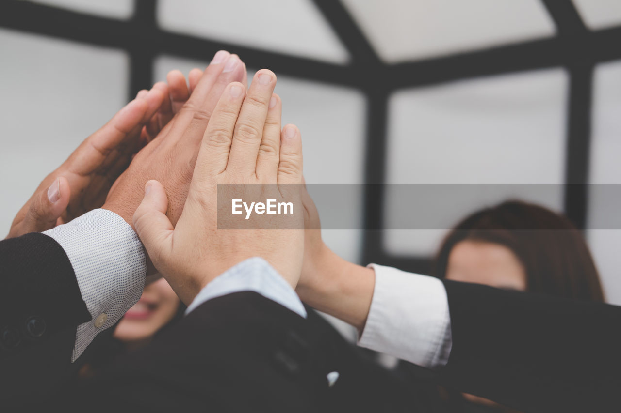 Cropped hand of business colleagues having high-five in office