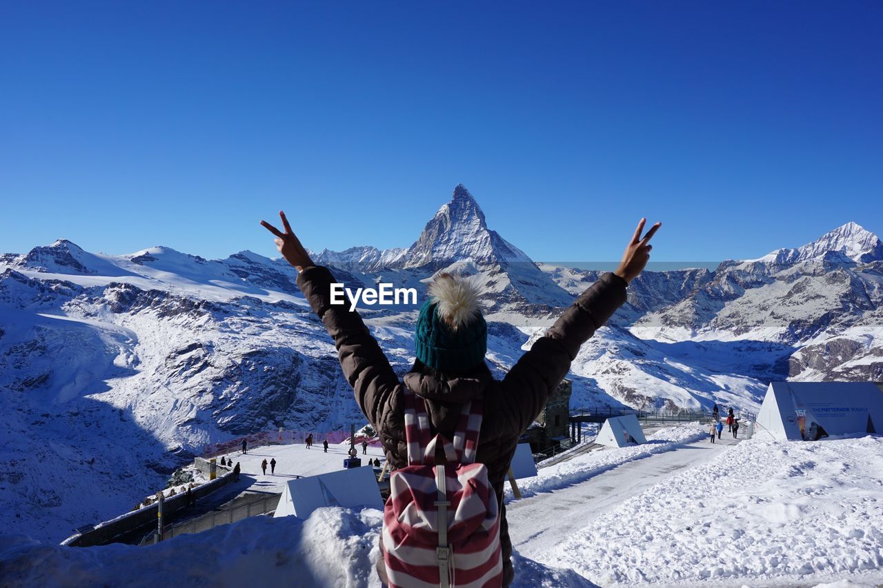 Woman in snow covered mountain against clear blue sky