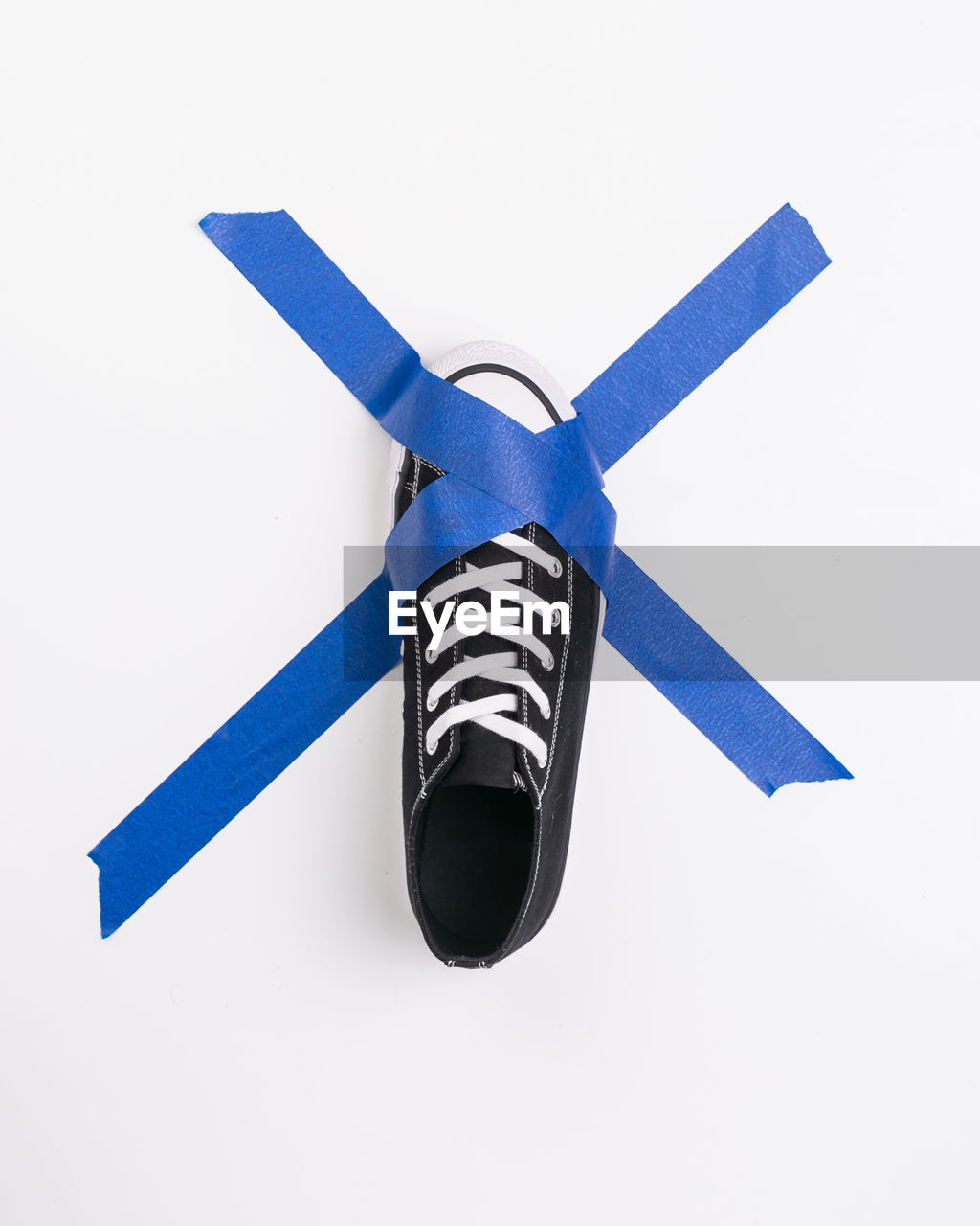 Directly above shot of canvas shoe and adhesive tape on white background