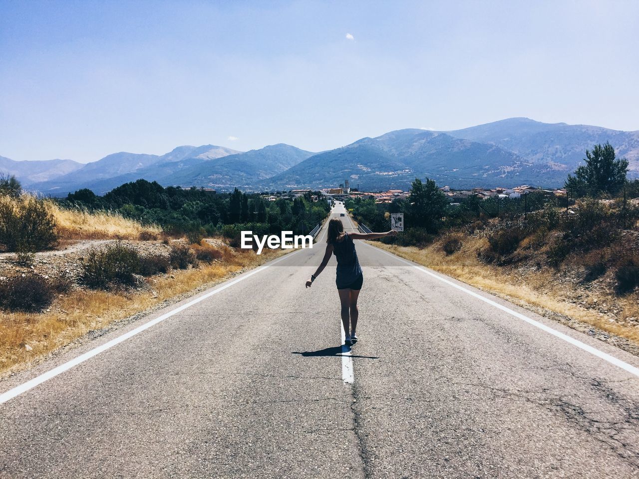 Rear view of woman walking on road against sky