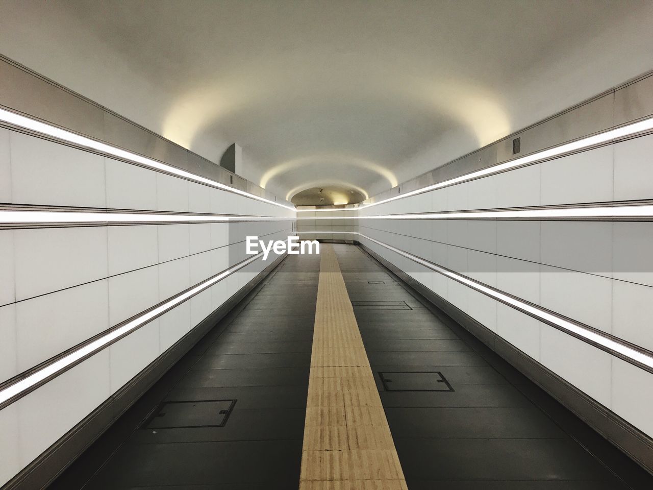 Empty illuminated tunnel with building in background