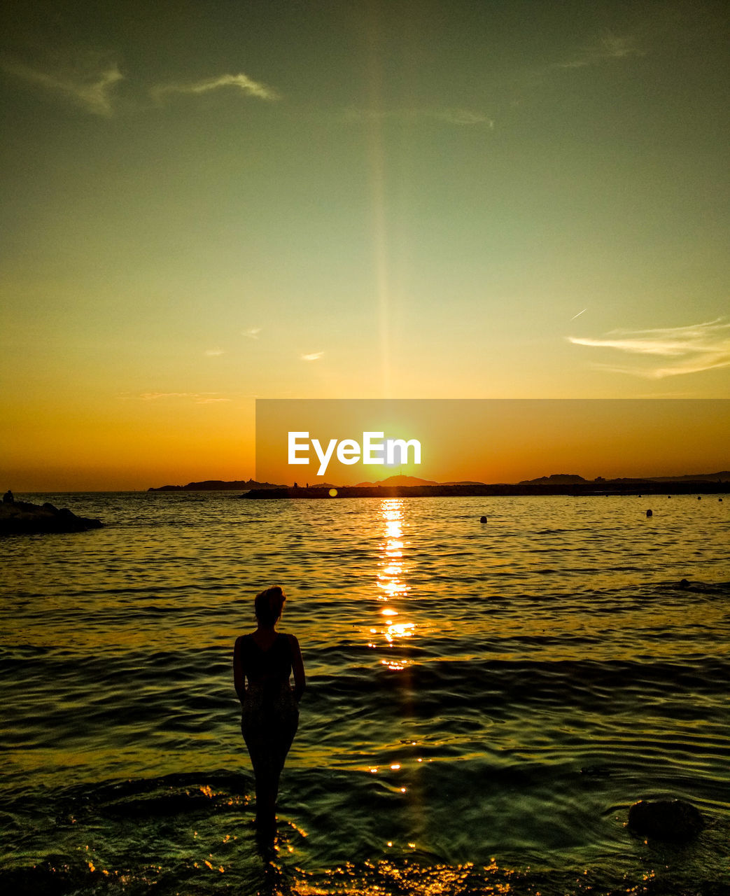 REAR VIEW OF SILHOUETTE MAN STANDING IN SEA AGAINST SKY