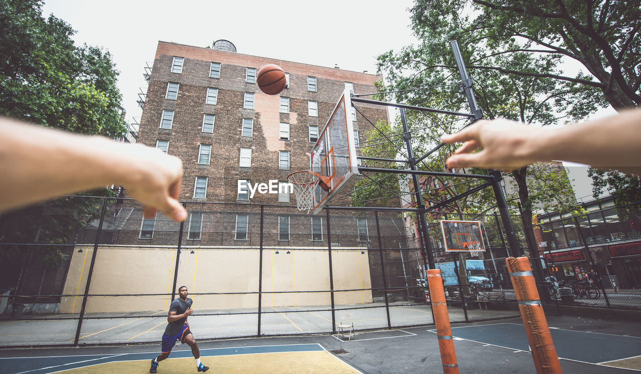 Cropped hands of person against man playing basketball at court