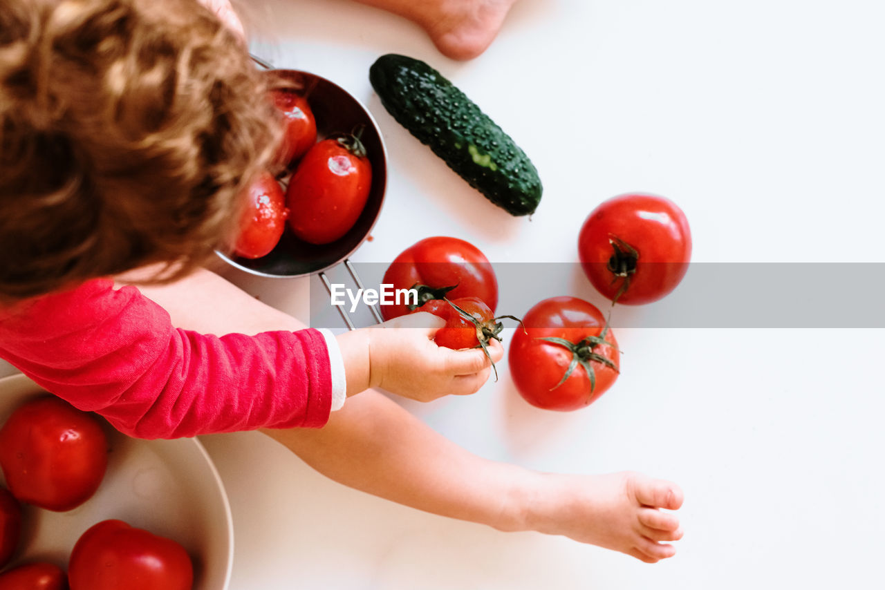 High angle view of baby with crushed tomatoes on table