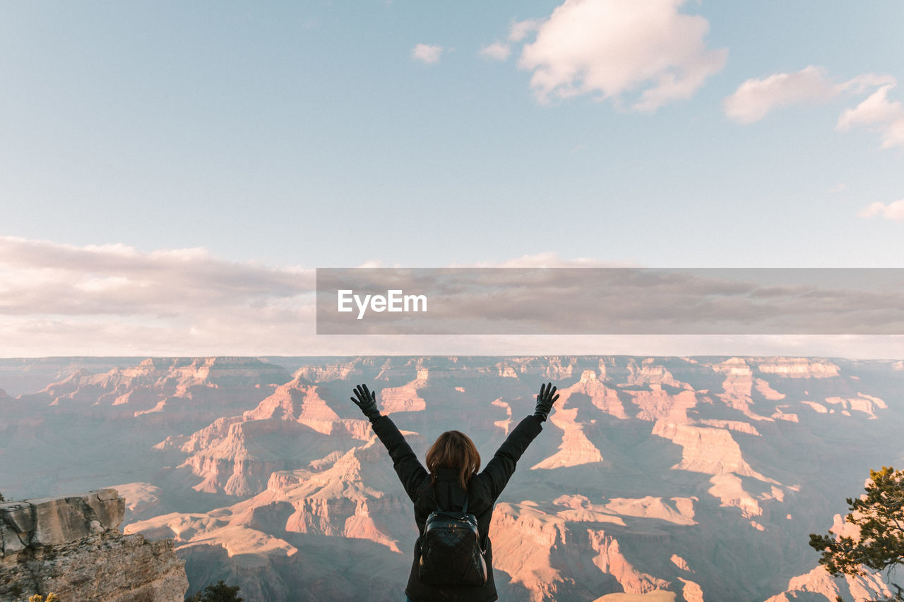 Rear view of female hiker with arms raised at grand canyon national park against sky