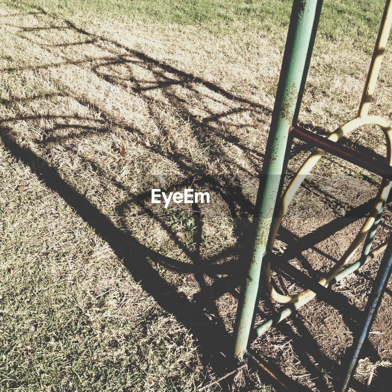 High angle view of jungle gym shadow on field at playground