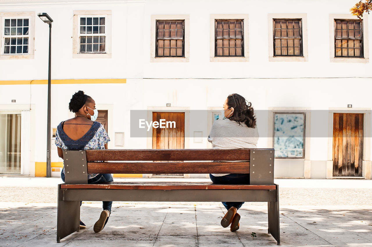 Woman sitting on bench against building