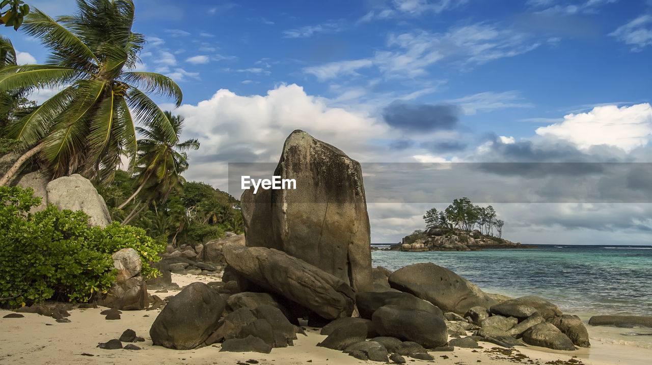 rock, sky, land, sea, water, beach, nature, cloud, body of water, tropical climate, shore, coast, palm tree, vacation, tree, scenics - nature, ocean, beauty in nature, sand, plant, travel destinations, tropics, tranquility, travel, environment, no people, landscape, tranquil scene, holiday, trip, outdoors, coastline, coconut palm tree, bay, day, island, idyllic, tourism, horizon over water, sunlight, blue, horizon