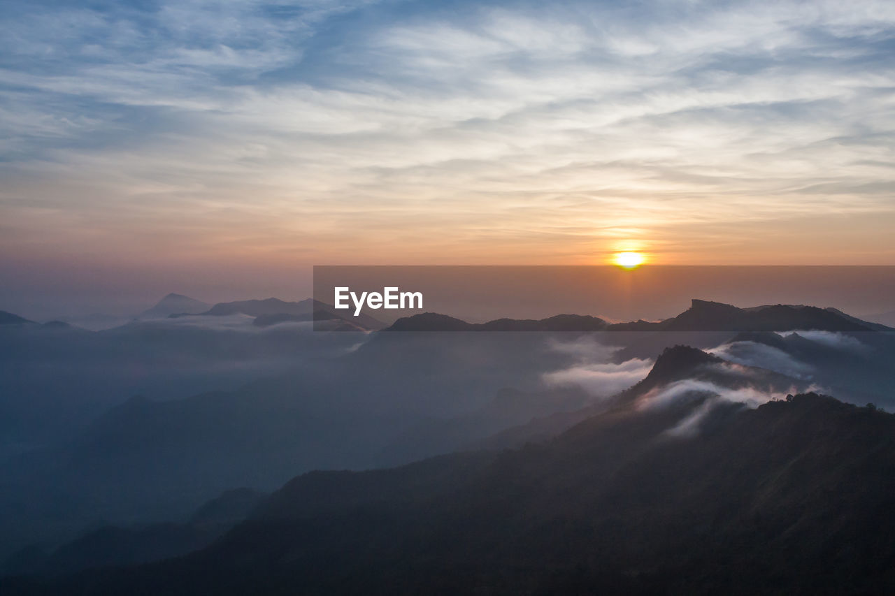 High angle view of mountains against cloudy sky at sunset