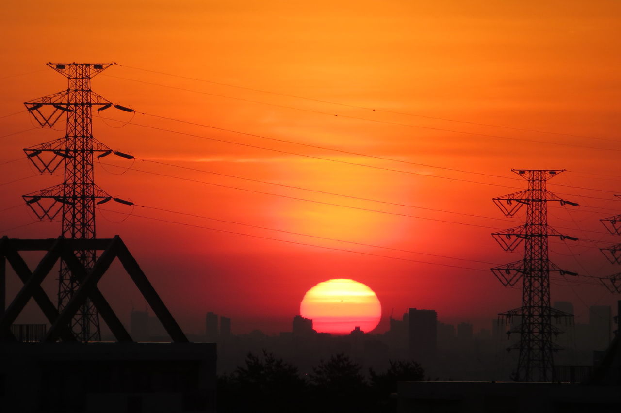 Low angle view of electricity pylon against sky during sunset