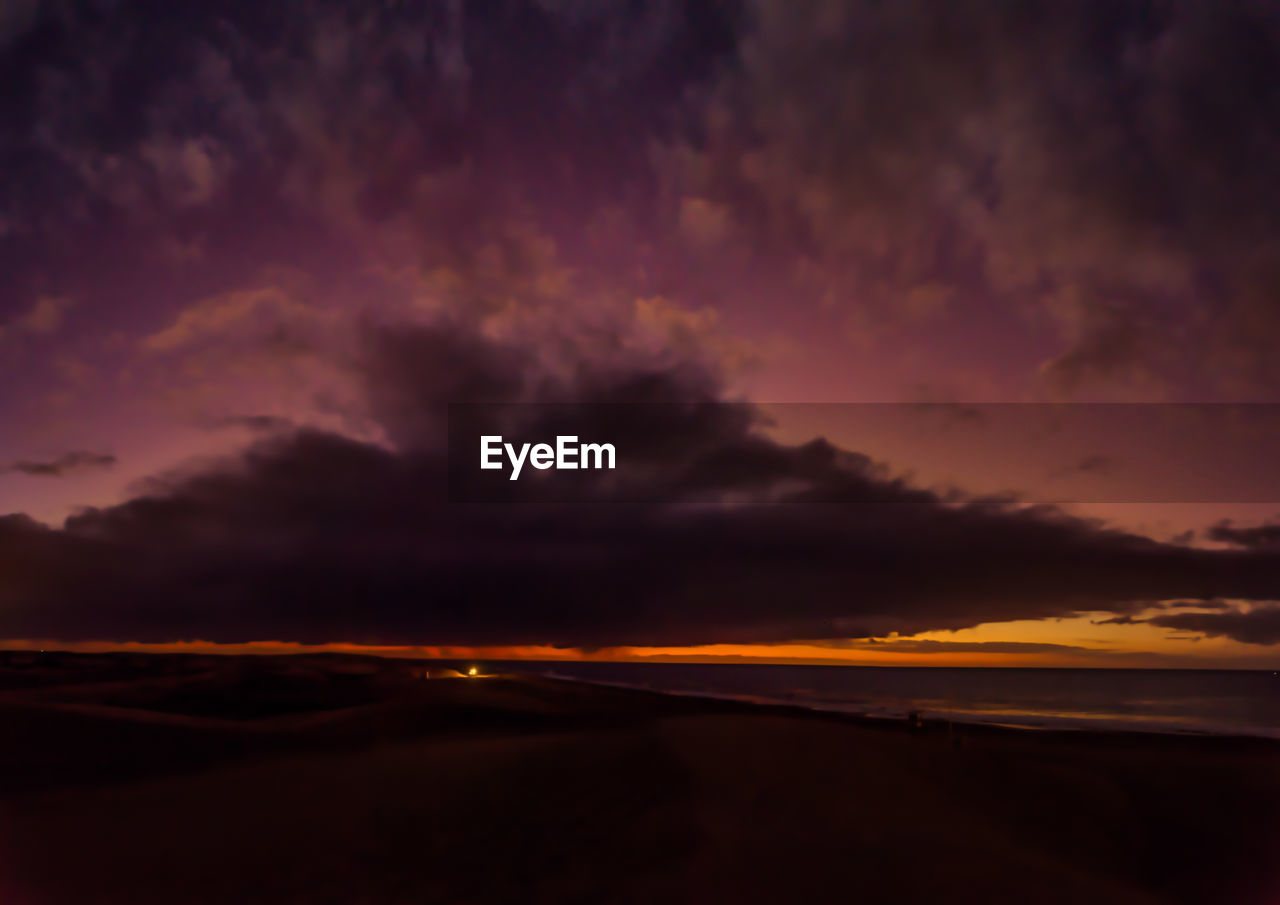 DRAMATIC SKY OVER SILHOUETTE LANDSCAPE DURING SUNSET