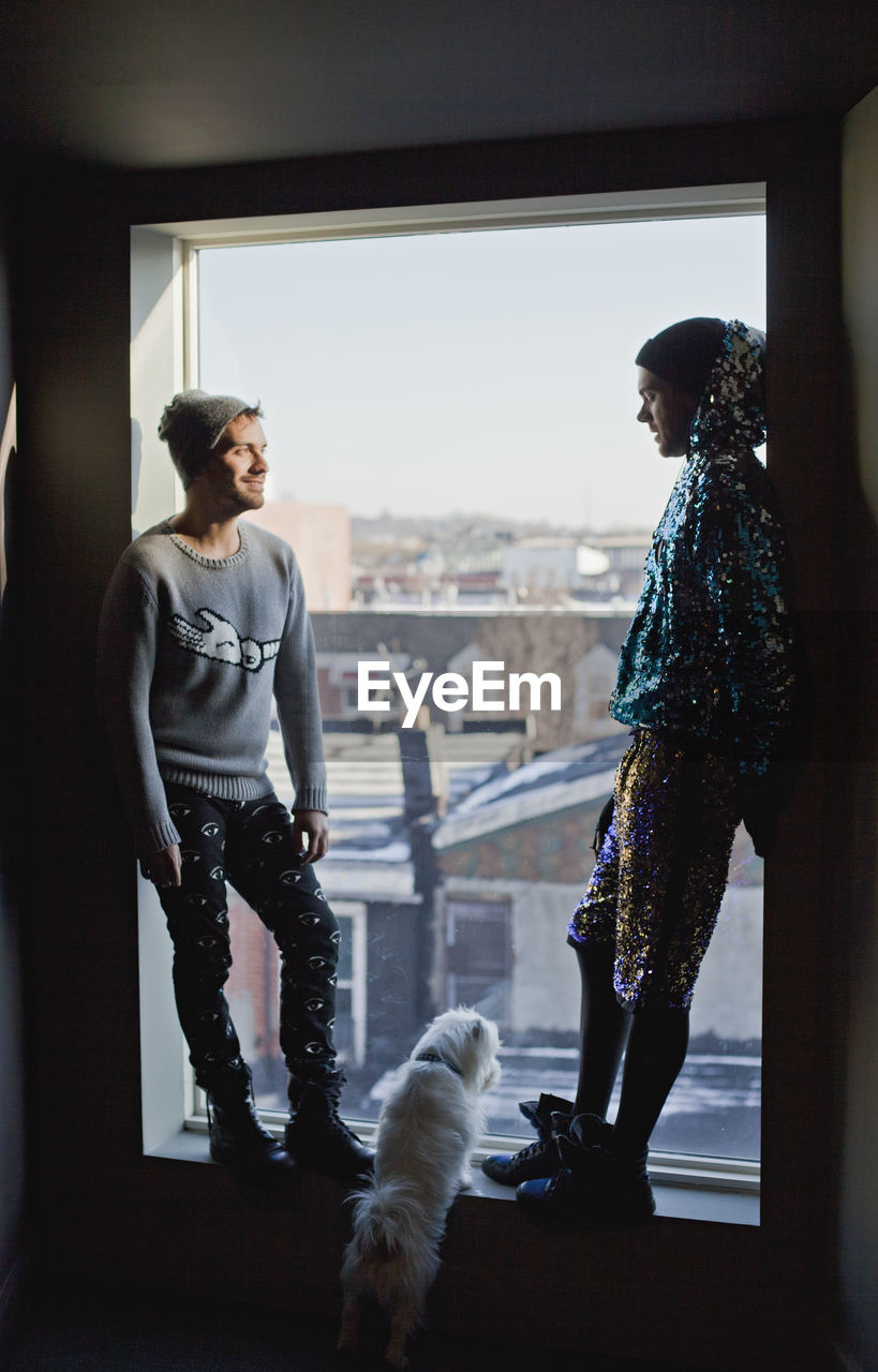 Young men standing in a window with their dog