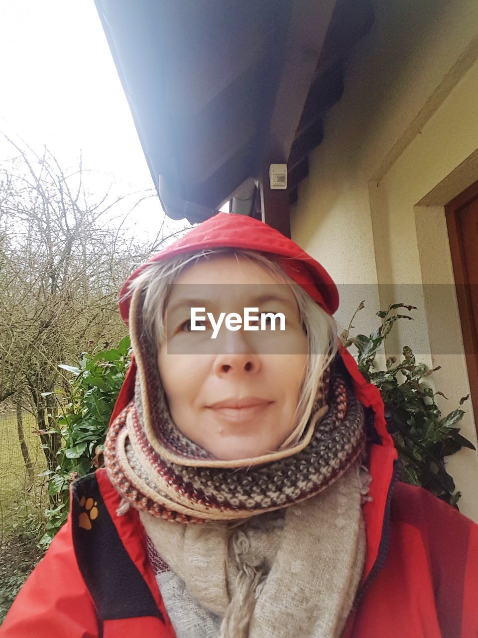 Close-up of mature woman standing by house