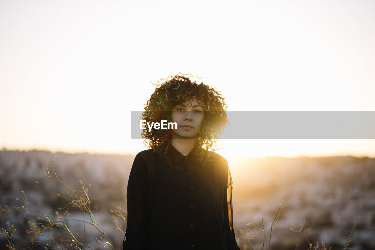Portrait of woman standing on land against sky during sunset