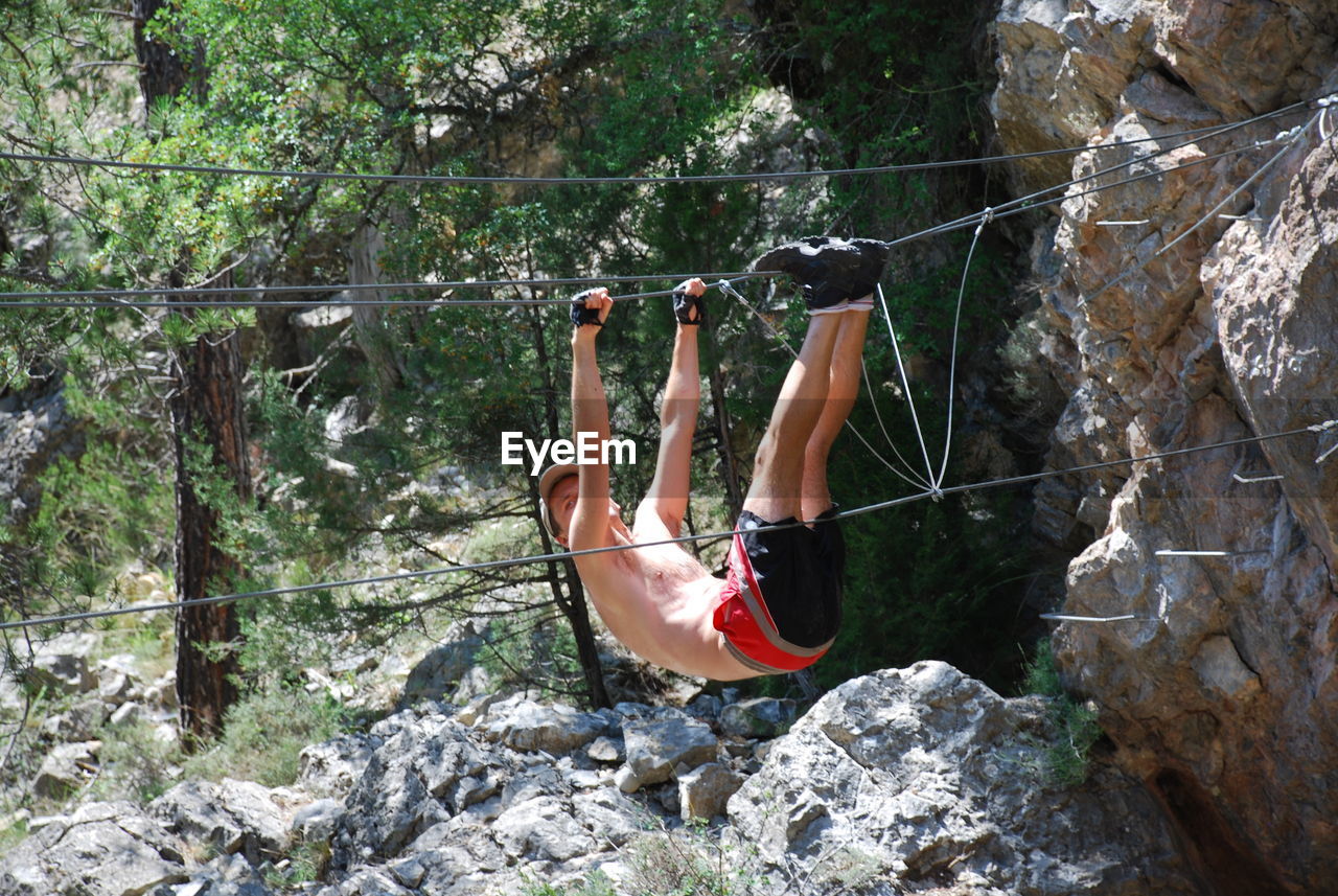 MIDSECTION OF WOMAN HANGING ON ROPE