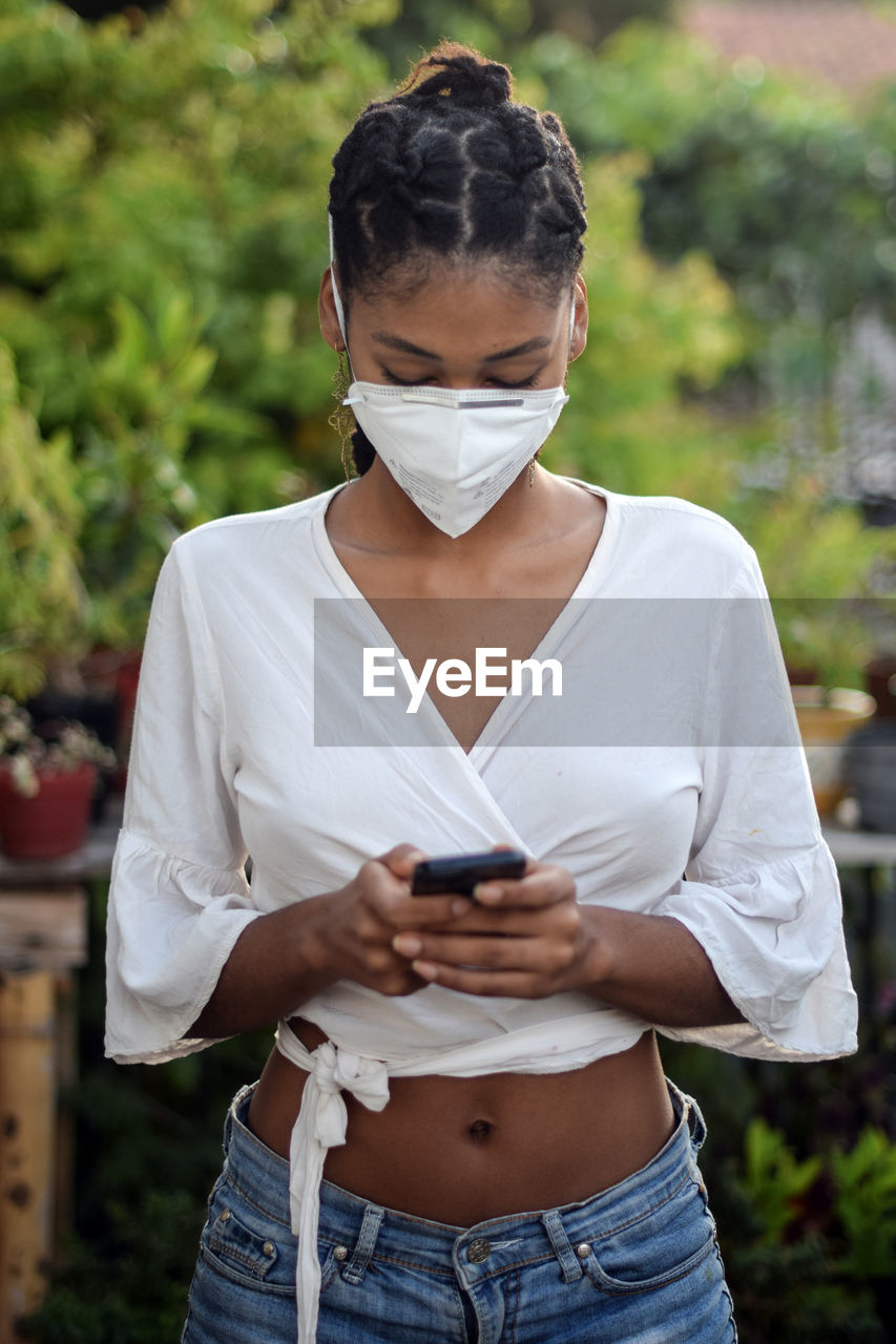 Young black woman in face mask using a smartphone