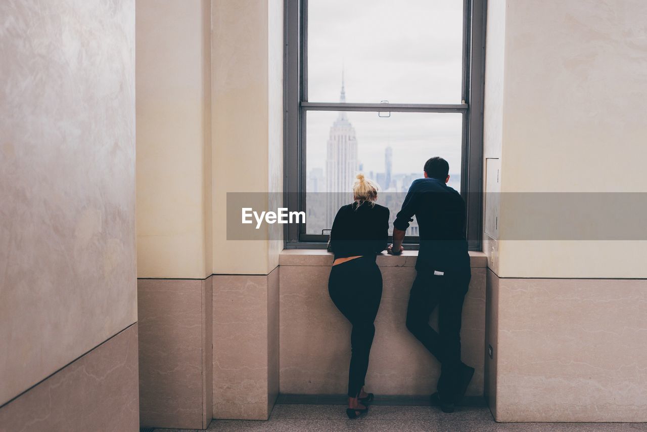 Rear view of people standing by window