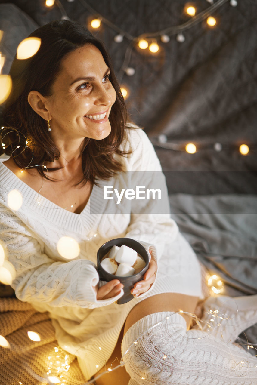 portrait of young woman holding christmas tree at night